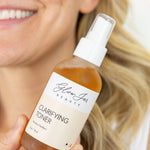 Bottle of Glow Jar Beauty Clarifying Toner held by a person with a blurred background