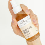 Hand holding a bottle of 'Glow Jar Beauty' clarifying toner against a white background