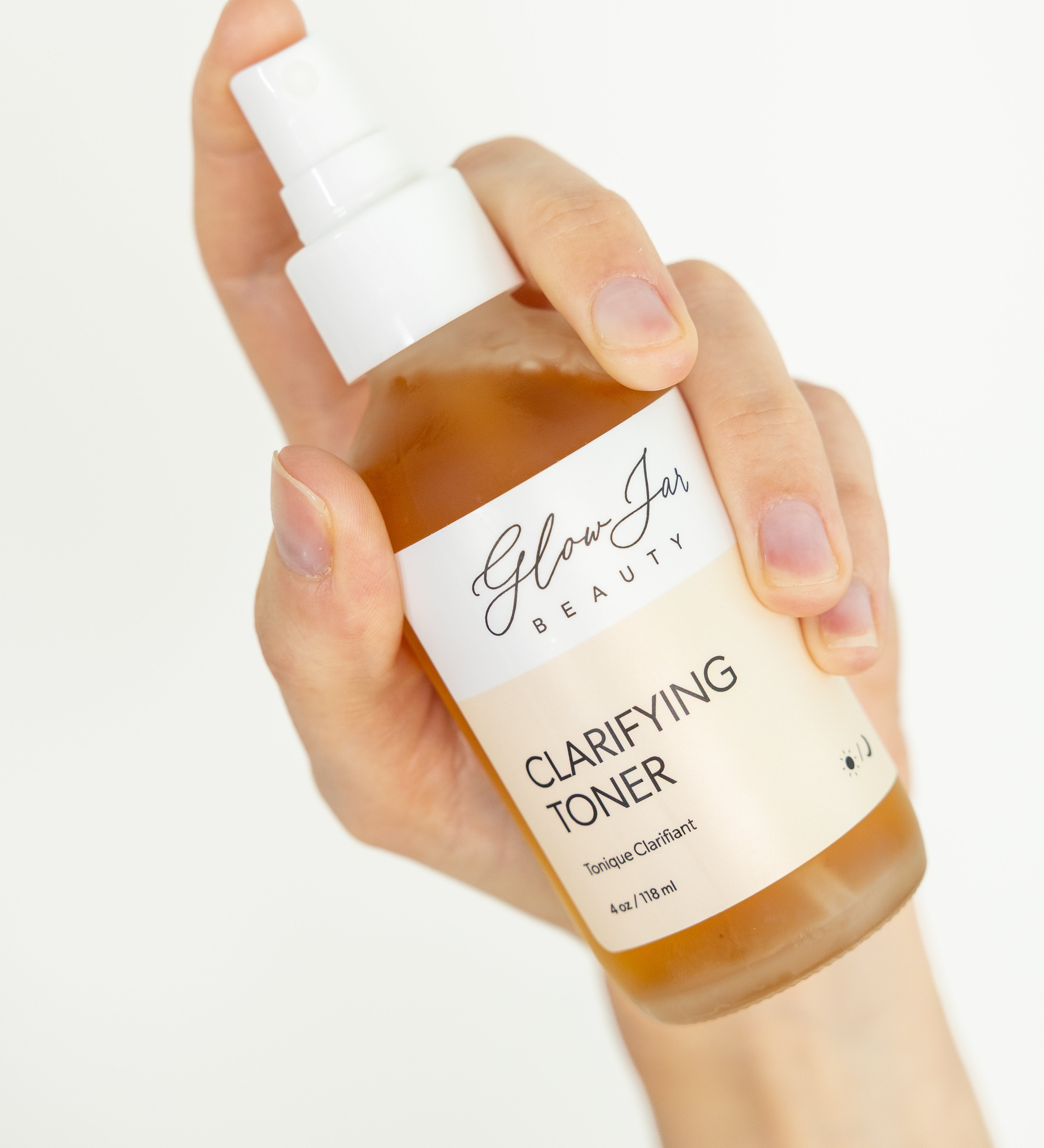 Hand holding a bottle of 'Glow Jar Beauty' clarifying toner against a white background