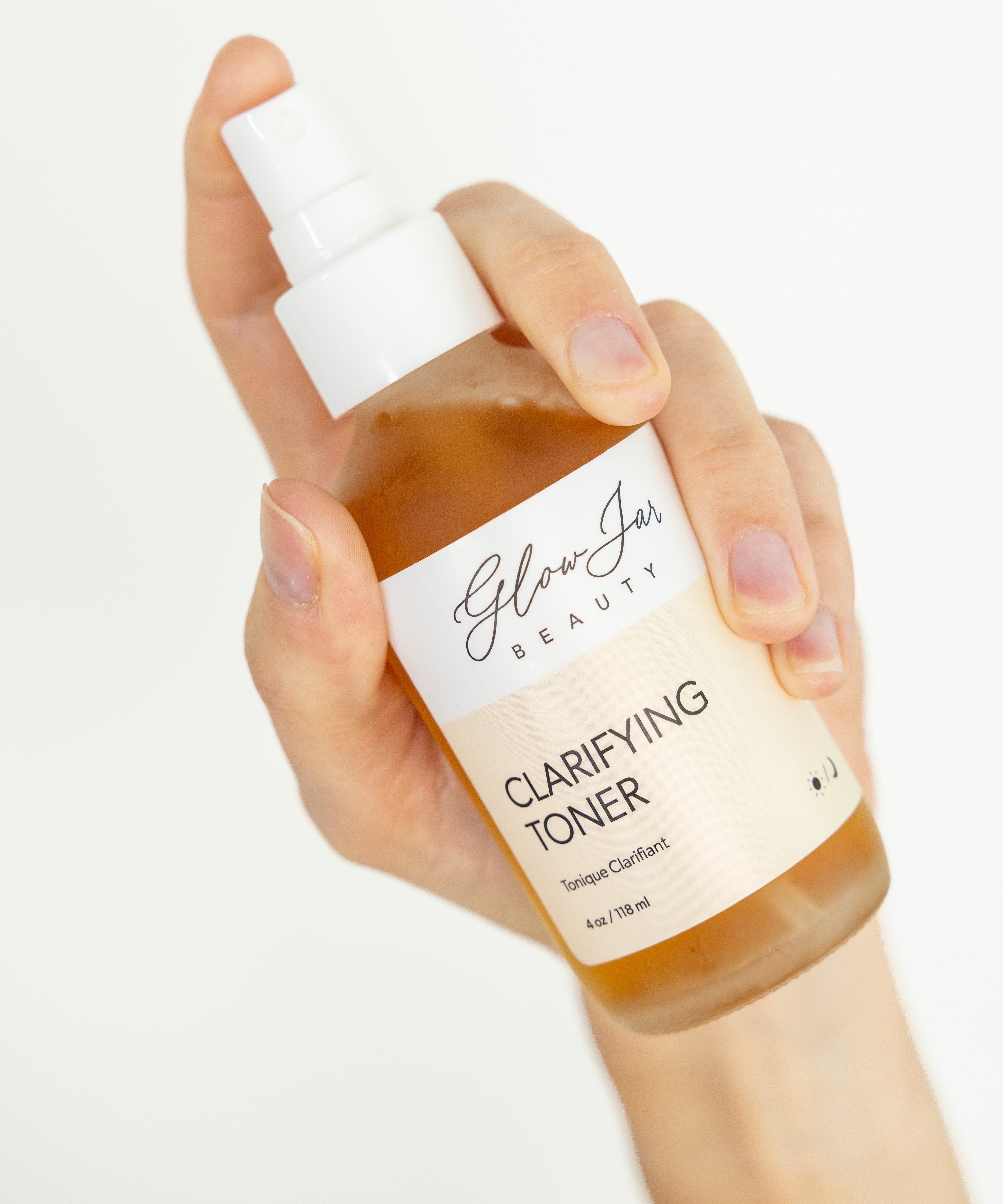 Hand holding a bottle of 'Glow Jar Beauty' clarifying toner against a white background
