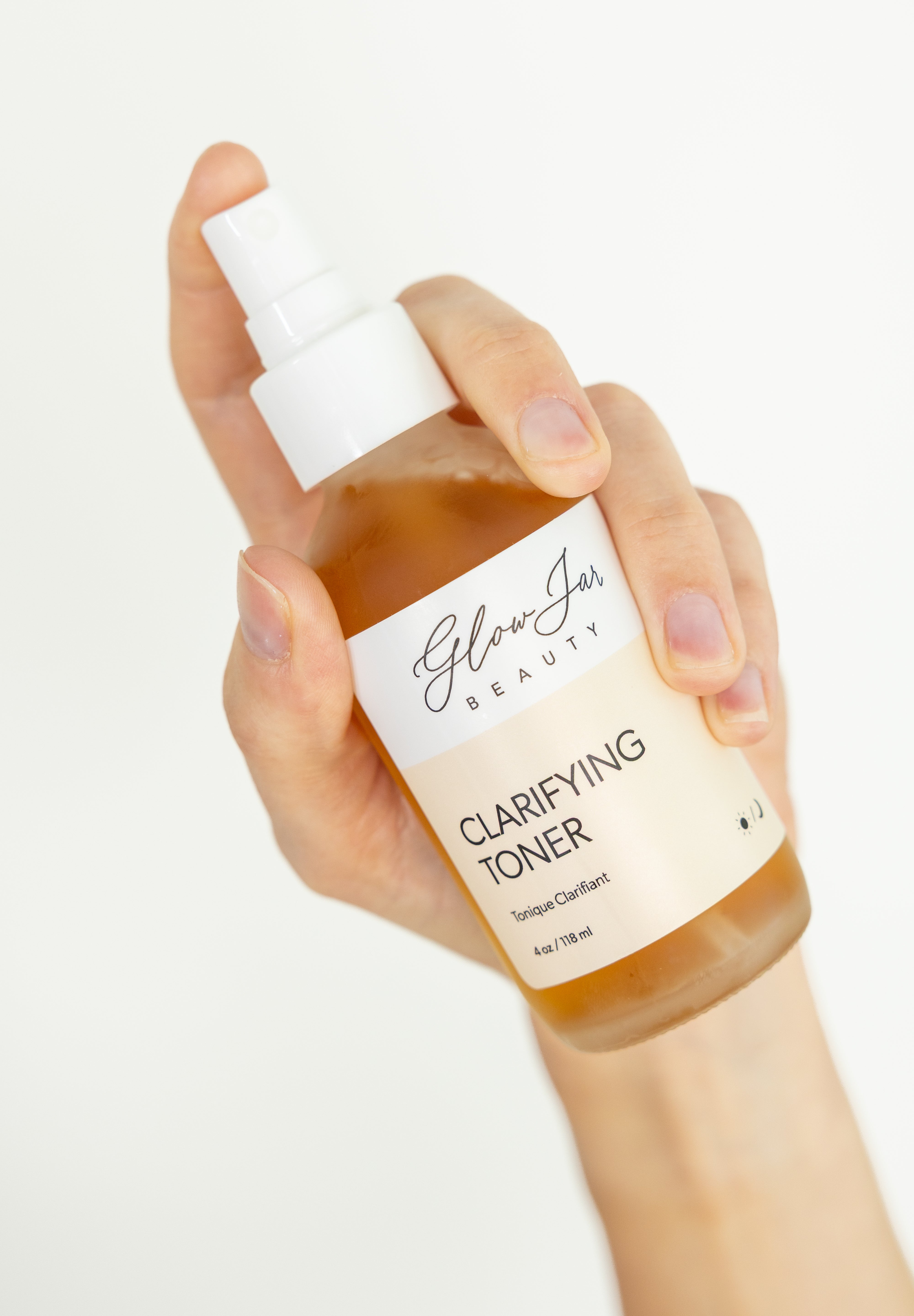 Hand holding a bottle of 'Glow Jar Beauty' clarifying toner against a white background