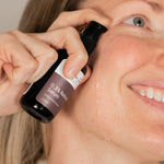 Person applying a retinol serum to their face with a neutral background