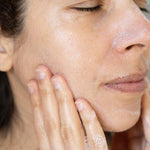 Woman applying a gentle gel cleanser to her face with her hands.