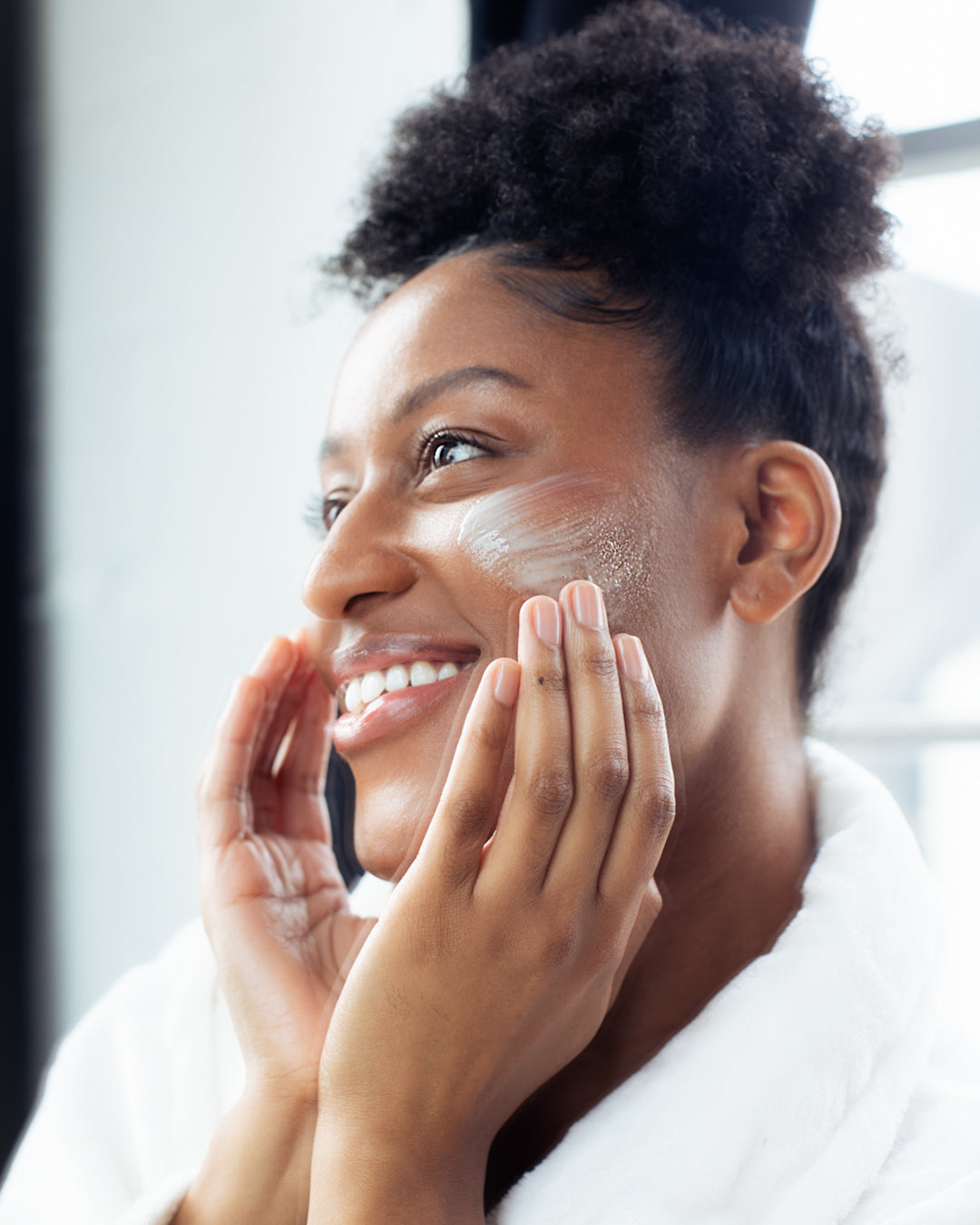 Woman applying moisturizing face cream to her face Glow Jar Beauty