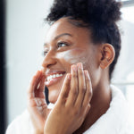 Woman applying moisturizing face cream to her face Glow Jar Beauty