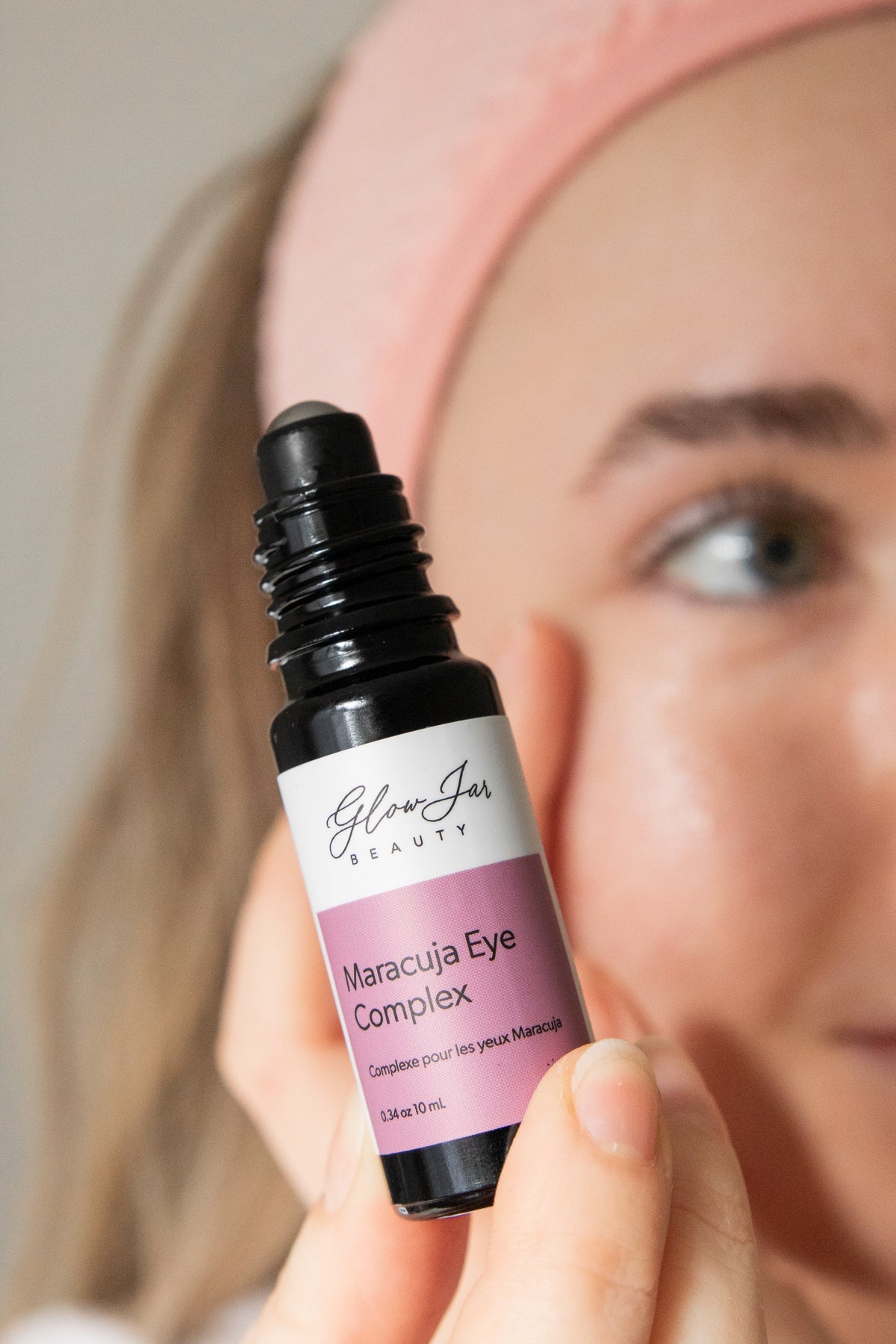 Glow Jar Beauty Maracuja Eye Complex bottle held by a person with a neutral background