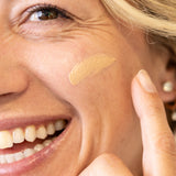 Woman applying a glow jar beauty tinted SPF 30 to her face with a finger