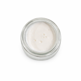 Small glass jar with white cream on a white background
