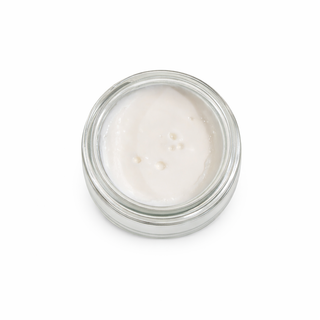 Small glass jar with white cream on a white background