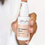 Hand holding a bottle of 8% Vitamin C Serum by Glow Jar Beauty against a white background
