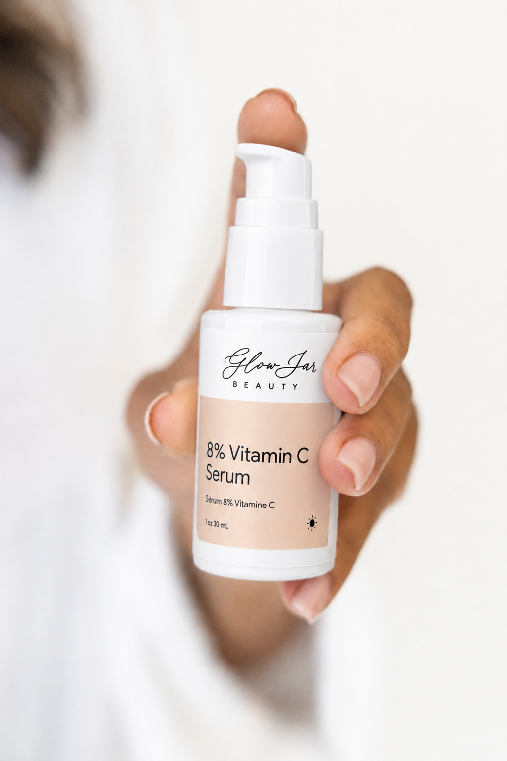 Hand holding a bottle of 8% Vitamin C Serum by Glow Jar Beauty against a white background