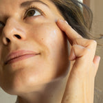 Close-up of a woman applying retinol to her face with her finger.